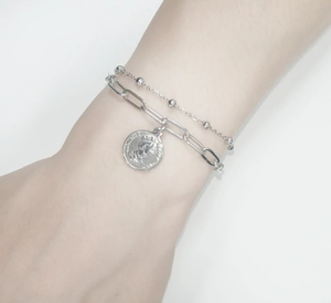 Détail d'un bracelet double couche argenté avec chaîne trombone et pendentif reine