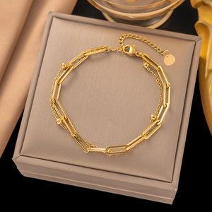 Gros plan sur le bracelet doré à double couche avec chaîne trombone et fermoir mousqueton