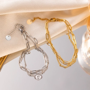 Détail de bracelets double couche dorés et argentés avec pendentifs pièces vintage
