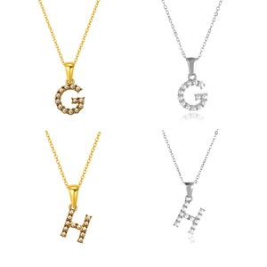 Detalle de los colgantes de letras G y H con micro perlas en acabados dorado y plateado