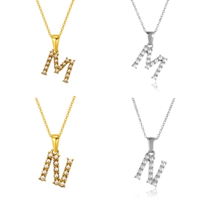 Detalle de colgantes de letras M y N con perlas blancas en acabados dorado y plateado
