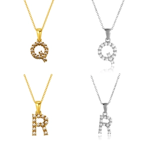 Detalle de los colgantes de letras Q y R con perlas en acabados oro y plata