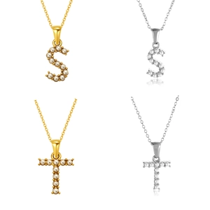 Detalle de colgantes de iniciales S y T con perlas en acabados dorado y plateado