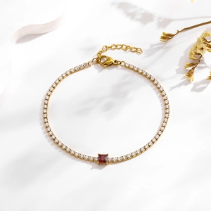 Detail of gold tennis bracelet with red square zircon and pavé crystals on white surface