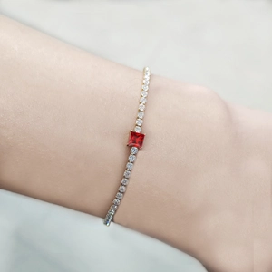 Detailed close-up of a gold chain bracelet with red zircon and sparkling clear stones