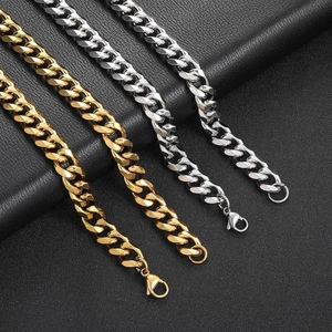 Detail of silver and gold Cuban link chains with lobster clasps on black leather surface