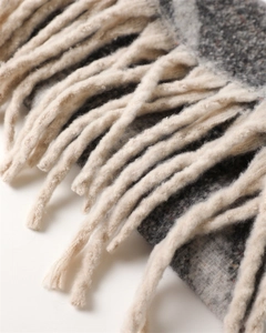 Close-up of thick grey and cream plaid cashmere-like scarf with knitted tassel details