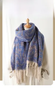 Detail of blue and brown geometric faux cashmere winter scarf with thick cream tassels