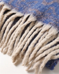 Detailed view of the dark blue jacquard fabric and long twisted tassels on the warm shawl