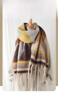 Close-up of winter scarf fringe detail with yellow and brown geometric patterns