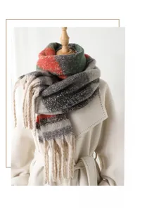 Detail view of tri-color geometric knit scarf with tassels on white coat