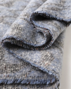 Detail of soft cashmere-like scarf showing blue mélange texture and fine tassel fringe