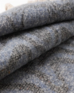 Close-up of soft cashmere-like texture on blue and grey plaid scarf with fringe details