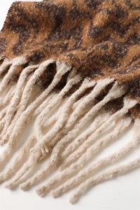 Close-up of geometric pattern knit scarf with thick cream tassels and wool texture
