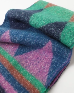 Close-up of thick geometric knit scarf with colorful blocks and soft fringe texture