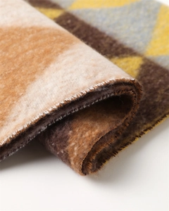 Close-up of thick geometric knit scarf showing soft texture and tassel edge details