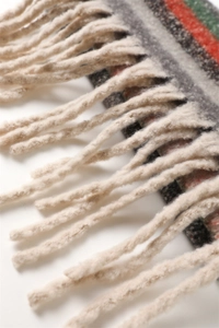 Close-up of fluffy tassels and multi-colored geometric stripes on a soft cashmere shawl