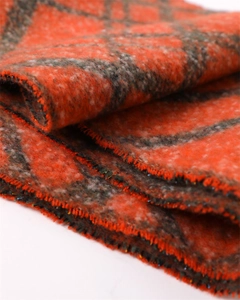 Close-up of orange and grey plaid scarf featuring soft fleece texture and fringe detail