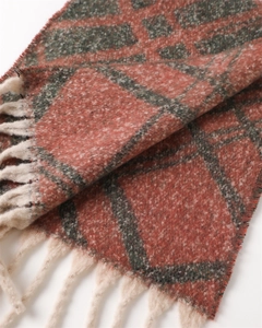 Close-up of thick knit plaid scarf featuring orange and green checks with tassels