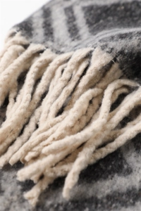 Vue macro de l'écharpe géométrique bleu marine et marron avec des pompons beiges