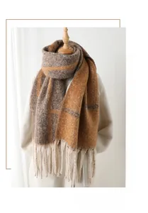 Close-up of thick plaid scarf texture with warm orange and brown tones and long fringes