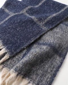 Close-up of blue and grey plaid scarf showing soft brushed texture and cream tassels