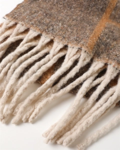 Close-up of thick plaid cashmere feel scarf featuring grey texture and yellow tassels