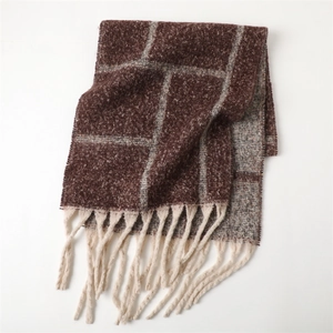 Detail of thick plaid cashmere scarf with dark brown gray checks and long cream tassels