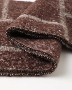 Close-up of thick plaid scarf fabric with soft cashmere texture and colorful stitched edges