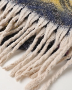 Macro detail of thick colorful cashmere shawl featuring chunky beige rope tassels