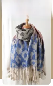 Detailed view of blue and grey leopard pattern winter scarf with soft fringe trim texture