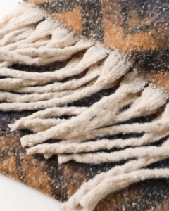 Detail of soft cashmere-like scarf with zigzag patterns and thick cream tassels