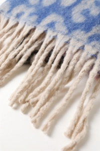 Detail shot of the jacquard pattern and long twisted fringe on the blue and beige scarf