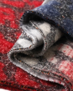Macro detail of thick faux cashmere scarf with red and blue pattern and lockstitch edges