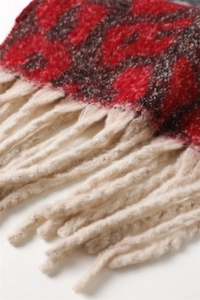Macro detail of red and black leopard knit fabric with thick cream twisted tassels