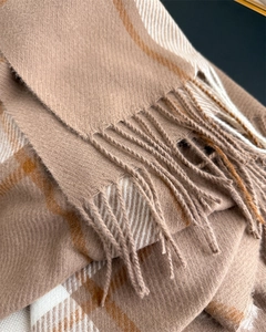 Macro view of plaid cashmere-like fabric showing herringbone weave and soft fringes