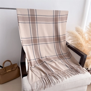 Detailed close-up of the beige plaid pattern and fringe tassels on the knit scarf