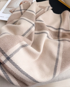 Detailed close-up of soft plaid cashmere scarf with tassels in beige and brown tones