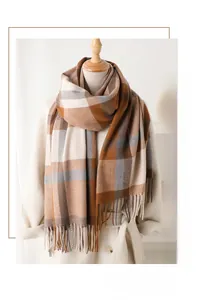 Detail of checkered cashmere-feel scarf with tassels draped on a white winter coat