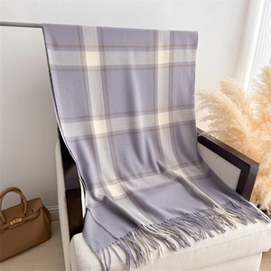Detailed view of lilac plaid cashmere-feel scarf with long fringes draped over a chair