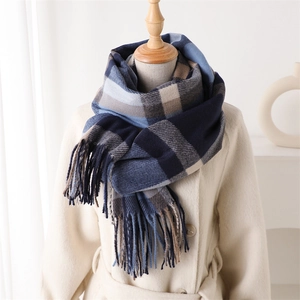 Detailed texture of a navy and beige plaid scarf with decorative tassels on a mannequin