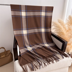Detail of soft plaid cashmere scarf with fringes draped over a white modern armchair