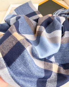 Close-up of blue and beige plaid scarf showing soft cashmere-like texture and fringe trim