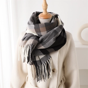 Close-up of thick plaid scarf with soft cashmere texture and tassel trim details