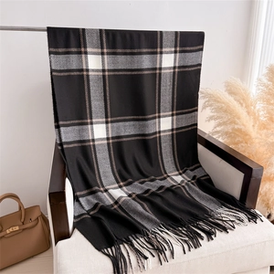 Close-up of classic checkered cashmere-like scarf featuring soft fringe and woven texture