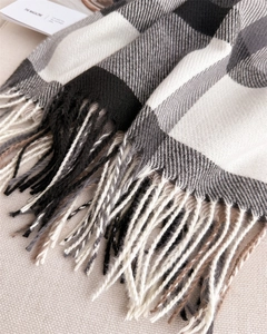 Macro detail of twill weave cashmere-like fabric and long fringe on a plaid scarf
