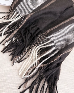 Detail shot of plaid scarf texture with woven tassels in black and caramel colors