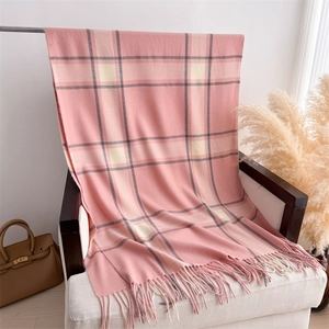 Close-up of pink plaid cashmere-feel scarf with soft fringe draping on a white chair