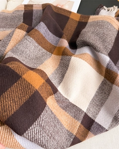 Close-up of soft plaid scarf fabric with orange and brown check and fringe details