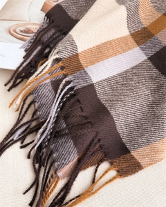 Detail of classic plaid scarf with soft fringe in brown, beige, and yellow tones